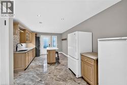 Recessed lighting, wood-finish cabinetry, tile flooring, mosaic tile backsplash, and a black gooseneck faucet - 