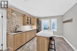 Laundry area featuring a built-in sink, wood-finish cabinetry, mosaic tile backsplash, and recessed lighting - 
