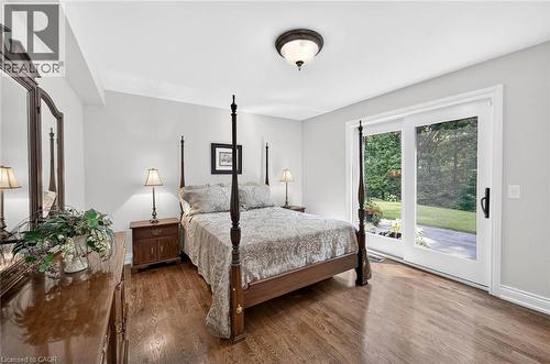 Wood-finish flooring throughout, white walls, and a white sliding glass door with a black handle - 11 Christman Court, Markham, ON - Indoor Photo Showing Bedroom