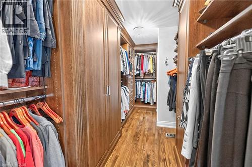 Custom wood-finish closet system with extensive built-in cabinetry, chrome hanging rods, and wood-finish flooring - 11 Christman Court, Markham, ON - Indoor With Storage