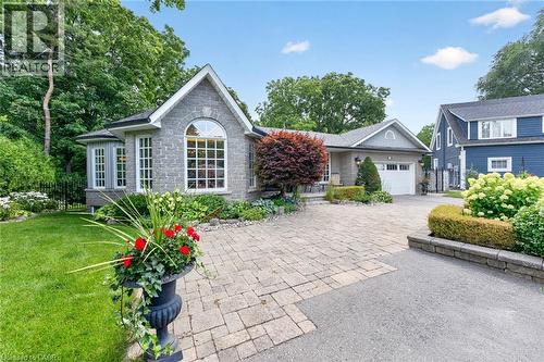 Stone facade with a prominent arched window, bay window, paver driveway, attached garage, and landscaped garden beds - 11 Christman Court, Markham, ON - Outdoor