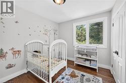 Recessed ceiling light fixture, hard surface flooring, white trim, white window frame, and white paneled door with black hardware - 
