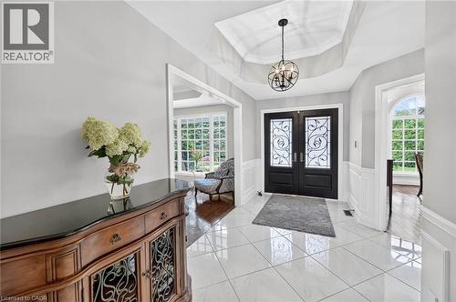 Double entry doors with decorative glass panels, tray ceiling with chandelier, white ceramic tile flooring, and wainscoting - 11 Christman Court, Markham, ON - Indoor Photo Showing Other Room