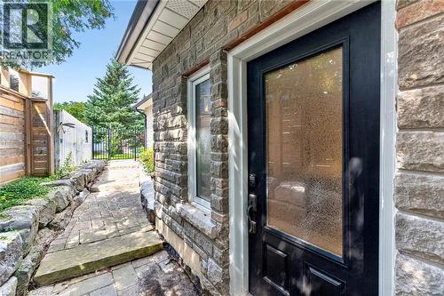 Stone facade with an opaque glass entry door, leading to a paver stone walkway with stone retaining walls, and a wrought iron gate - 11 Christman Court, Markham, ON - Outdoor With Exterior