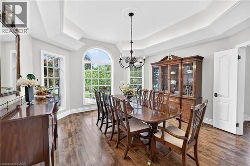 Tray ceiling with a decorative chandelier, wood-finish flooring, and multiple gridded windows including an arched window - 11 Christman Court, Markham, ON - Indoor Photo Showing Dining Room