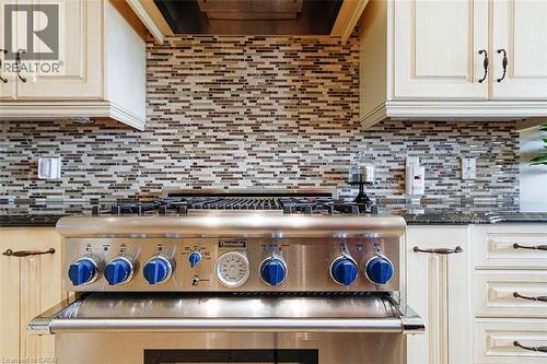 Kitchen featuring dark stone countertops, high end stainless steel range oven, extractor fan, and backsplash - 205 Paige Place, Kitchener, ON 