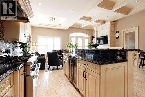 Kitchen with open floor plan, dark stone counters, stainless steel range, extractor fan, and stone tile flooring - 205 Paige Place, Kitchener, ON 