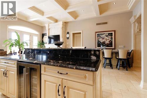 Kitchen featuring wine cooler, dark stone countertops, stone tile floors, coffered ceiling, and light wood finish cabinetry - 205 Paige Place, Kitchener, ON 