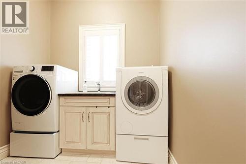 Laundry room featuring cabinet space, independent washer and dryer, and light tile patterned floors - 205 Paige Place, Kitchener, ON 