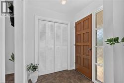 Entryway featuring a paneled wood door with a sidelight, white louvered bifold closet doors, and patterned floor tile - 