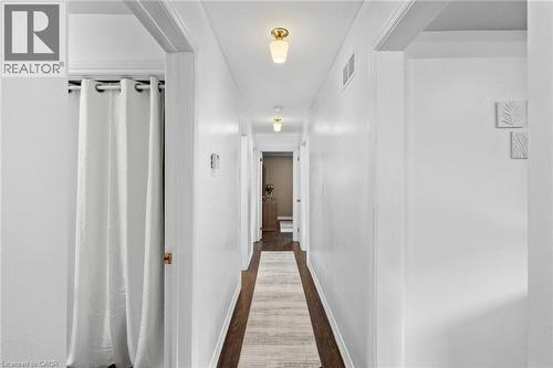 Hallway featuring dark wood-finish flooring, white walls, and flush-mount lighting fixtures - 1083 Melton Drive, Mississauga, ON 