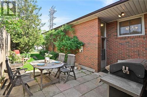 Rear patio featuring square pavers and a brick exterior, surrounded by mature plants and a fenced perimeter - 1083 Melton Drive, Mississauga, ON 
