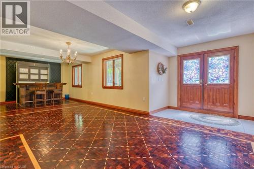 Spacious open-concept entertaining area featuring rich wood-finish flooring with geometric inlay detailing, decorative crown molding, and recessed ceiling lighting - 23 Susan Drive, Hamilton, ON 