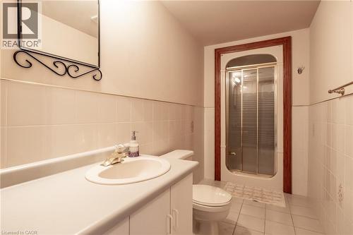 Full bathroom featuring a ceramic tile surround, white vanity with integrated sink and countertop, and ceramic tile flooring - 23 Susan Drive, Hamilton, ON 
