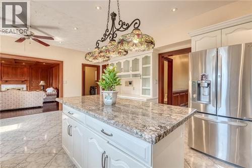Kitchen island with a granite countertop, white cabinetry, and decorative pendant lighting - 23 Susan Drive, Hamilton, ON 