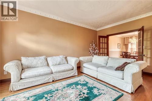 Hardwood-style flooring, crown molding, and French doors with glass panels create an inviting atmosphere - 23 Susan Drive, Hamilton, ON 