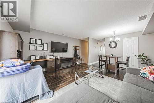 Open-concept living area featuring wood-finish flooring, a built-in electric fireplace, and a dining area with a chandelier - 266 Limeridge Road E Unit# 3, Hamilton, ON 