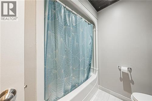 Tub/shower combination with white surround, light gray walls, and wood-finish ceiling accent - 266 Limeridge Road E Unit# 3, Hamilton, ON 