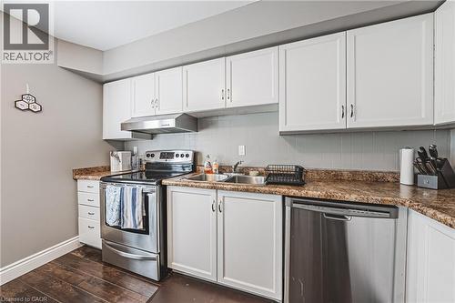 Kitchen featuring white cabinetry, wood-finish flooring, stainless steel appliances, a double basin sink, and laminate countertops - 266 Limeridge Road E Unit# 3, Hamilton, ON 