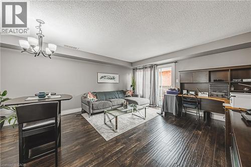 Wood-finish flooring throughout, complemented by a contemporary chandelier and a built-in dark wood desk unit - 266 Limeridge Road E Unit# 3, Hamilton, ON 