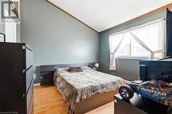 Sloped ceiling with wood-finish trim, light wood-finish flooring, and a window with blinds - 