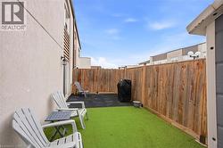 Private outdoor space featuring artificial turf, rubber matting, and a wood privacy fence - 