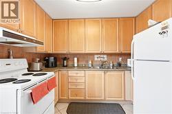 Kitchen featuring extensive wood cabinetry, tile flooring, and a stainless steel double basin sink - 
