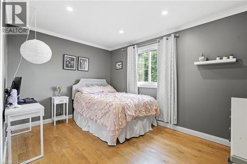 Spacious room featuring wood-finish flooring, recessed lighting, and a window with white trim - 72 Crestlynn Crescent, Simcoe, ON 