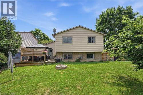 Expansive backyard featuring a wood-finish deck with privacy fencing, a freestanding gazebo, a built-in stone fire pit, and a grassy lawn - 72 Crestlynn Crescent, Simcoe, ON 