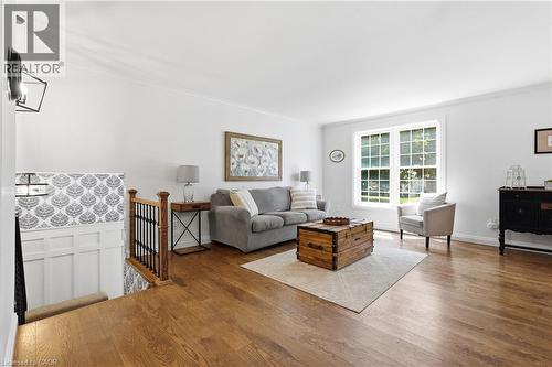 Bright living room featuring wood-finish flooring, white walls, and crown molding - 72 Crestlynn Crescent, Simcoe, ON 