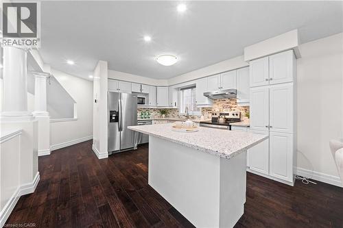 Kitchen featuring a center island with a light-toned countertop, white cabinetry, stainless steel appliances, and a tiled backsplash - 495 Brigantine Drive, Waterloo, ON 
