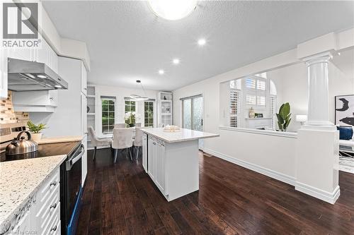 Kitchen featuring white cabinetry, light-toned countertops, a tile backsplash, and dark wood-finish flooring - 495 Brigantine Drive, Waterloo, ON 