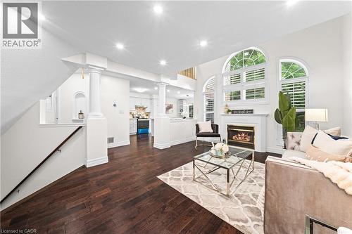 Recessed lighting, wood-finish flooring, white fireplace with mantel, arched windows with shutters, and architectural columns - 495 Brigantine Drive, Waterloo, ON 