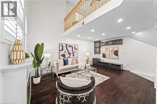 Vaulted ceilings, wood-finish flooring, built-in media console, upper cabinetry with glass fronts, and a natural wood railing - 495 Brigantine Drive, Waterloo, ON 