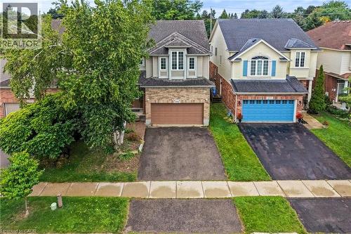 Two-story residence with a front-facing garage and an asphalt driveway, featuring mature trees and a walkway - 495 Brigantine Drive, Waterloo, ON 