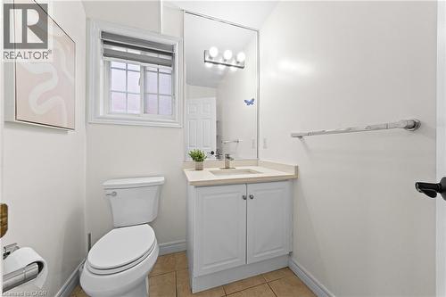 Window with privacy blind, white vanity with integrated sink, polished chrome faucet, full-width mirror, and three-light fixture - 495 Brigantine Drive, Waterloo, ON 