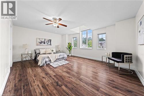 Wood-finish flooring throughout, multiple windows providing natural light, a ceiling fan with integrated lighting, and white baseboards - 495 Brigantine Drive, Waterloo, ON 