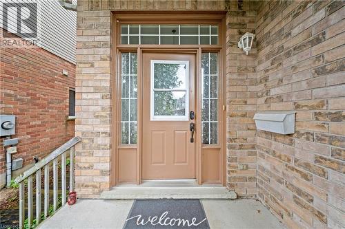 Brick exterior with a brown entry door, sidelight windows, and a transom window - 495 Brigantine Drive, Waterloo, ON 