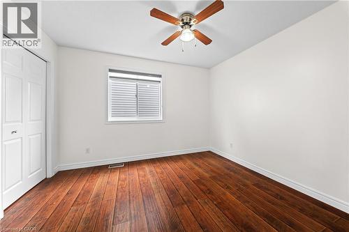 Wood-finish flooring with white trim, a double-door closet, a window with blinds, and a ceiling fan with light fixture - 495 Brigantine Drive, Waterloo, ON 