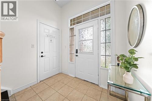 Entryway featuring a main door with decorative glass, two side panels with textured glass, a transom window, and square tile flooring - 495 Brigantine Drive, Waterloo, ON 