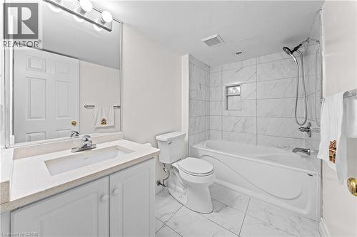 Bathroom featuring a vanity with an integrated sink, a large wall-mounted mirror, white shaker-style cabinetry, and a bathtub with a tiled surround - 495 Brigantine Drive, Waterloo, ON 