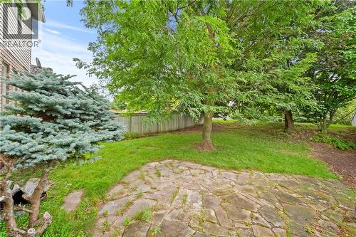 Expansive outdoor space featuring a flagstone patio, mature trees, and a privacy fence - 495 Brigantine Drive, Waterloo, ON 
