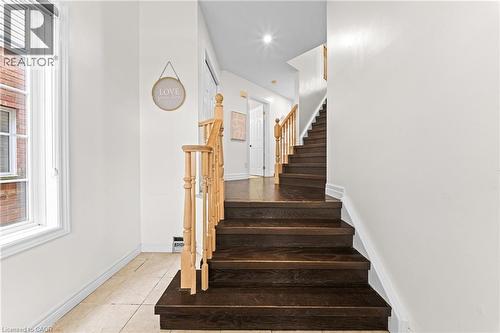 Dark wood-finish staircase with light wood railings, white walls, and ceramic tile flooring - 495 Brigantine Drive, Waterloo, ON 