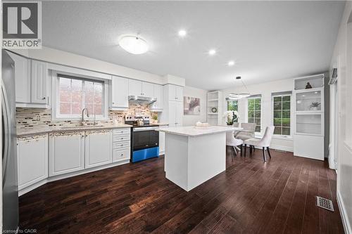 White cabinetry, wood-finish flooring, recessed lighting, central island with seating, and integrated shelving - 495 Brigantine Drive, Waterloo, ON 