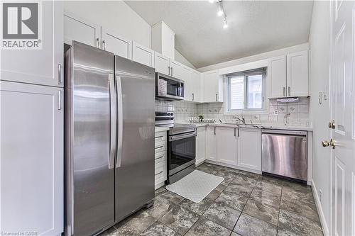 Kitchen featuring white cabinetry, stainless steel appliances, tile flooring, and a window - 168 Copper Leaf Street, Kitchener, ON 