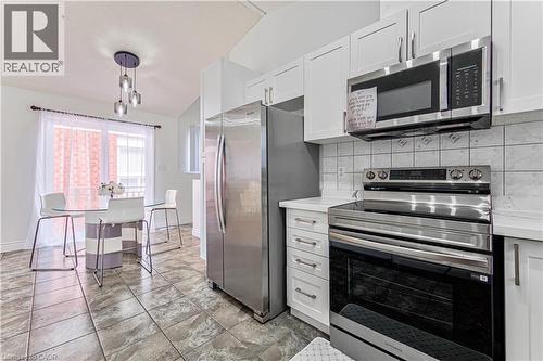 Kitchen featuring stainless steel appliances, white cabinetry, a tiled backsplash, and stone-look flooring - 168 Copper Leaf Street, Kitchener, ON 