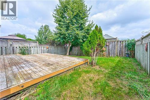 Expansive backyard featuring a wood deck, wood fencing, and mature trees - 168 Copper Leaf Street, Kitchener, ON 
