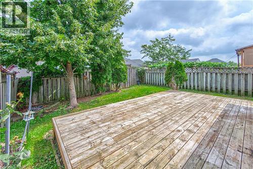 Expansive wood deck with surrounding green lawn, mature trees, and a wooden privacy fence - 168 Copper Leaf Street, Kitchener, ON 