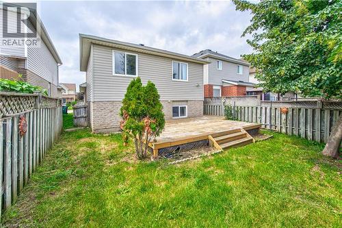 Rear exterior featuring a wooden deck with steps, a fenced yard, and light-colored siding - 168 Copper Leaf Street, Kitchener, ON 