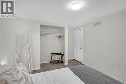 Bedroom featuring wood-finish flooring, recessed closet with hanging rod, white door with black hardware, white baseboards, and a flush-mount ceiling light fixture - 